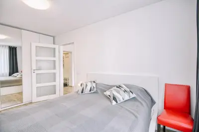 a bedroom with a bed and a red chair at DaGys apartments in Druskininkai