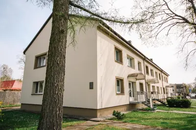a white building with a tree in front of it at DaGys apartments in Druskininkai