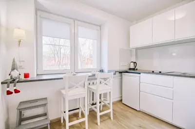a white kitchen with white cabinets and white stools at DaGys apartments in Druskininkai
