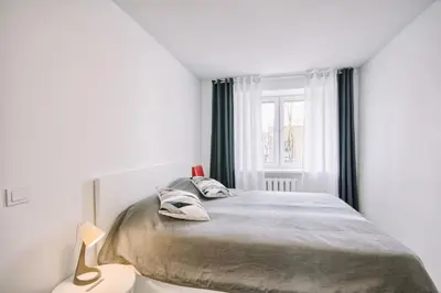a white bedroom with a bed and a window at DaGys apartments in Druskininkai