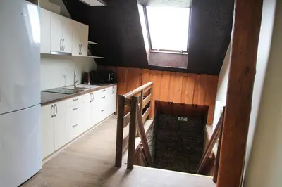 a kitchen with white cabinets and a staircase with a window at Vila Romnesa in Ignalina
