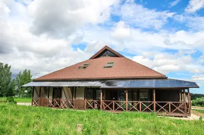 a large building with a brown roof on a field at Vila Romnesa in Ignalina