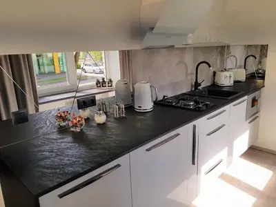 a kitchen with white cabinets and a black counter top at Apartment For You in Šiauliai
