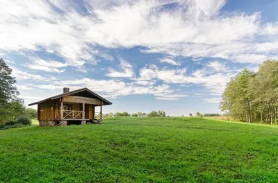 a small cabin in a field of green grass at Sauna with the Private Lake Access in Molėtai