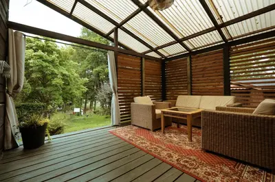 an outdoor patio with a pergola and furniture on a deck at Akmenos Villas & Bungalow in Bražuolė