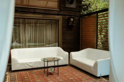 two white couches and a coffee table on a porch at Akmenos Villas & Bungalow in Bražuolė