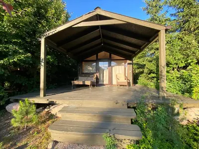 a wooden gazebo with a bench and a table at Akmenos Villas & Bungalow in Bražuolė