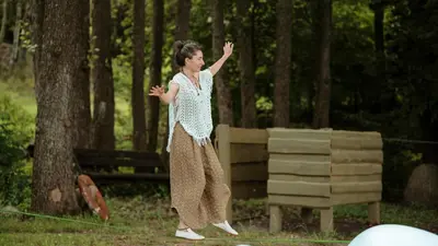 a woman standing on a rope in the woods at Akmenos Villas & Bungalow in Bražuolė