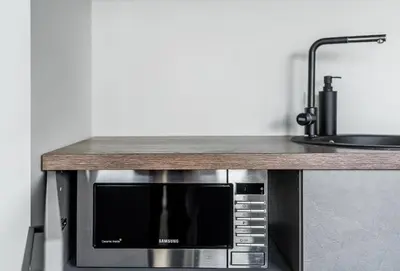 a microwave oven sitting under a counter in a kitchen at CUTE Apartment Šiauliai FREE Parking in Šiauliai