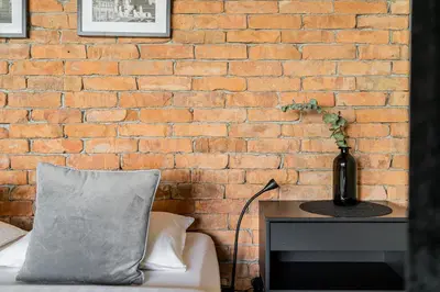 a brick wall with a couch and a vase on a table at CUTE Apartment Šiauliai FREE Parking in Šiauliai