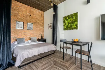 a bedroom with a bed and a table and a brick wall at CUTE Apartment Šiauliai FREE Parking in Šiauliai