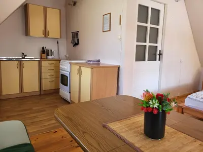 a living room with a table and a kitchen at Sodyba - Antalieptės marios in Zarasai