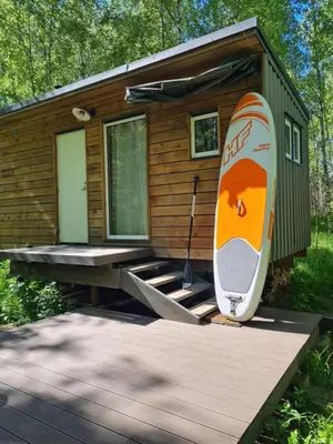 a tiny house with a surfboard sitting on a deck at Inkilas in Sidabrinės