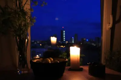 a candle and a window with a view of a city at Penthouse Apartment with Great Panoramic City View in Vilnius