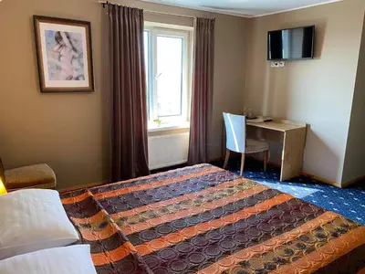 a hotel room with a bed and a desk and a window at Šeduvos malūnas in Šiauliai