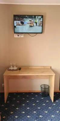 a television hanging on a wall with a wooden table at Šeduvos malūnas in Šiauliai