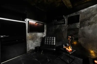 a dark room with a chair and a table with candles at Apartments in Kaunas city centre with Jacuzzi bath in Kaunas