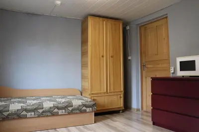 a bedroom with a bed and a cabinet and a television at Nakvynė apgyvendinimo paslaugos DAIVOS NAKVYNĖS NAMAI in Biržai