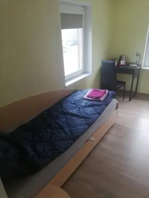a bed in a room with a desk and a window at Nakvynė apgyvendinimo paslaugos DAIVOS NAKVYNĖS NAMAI in Biržai