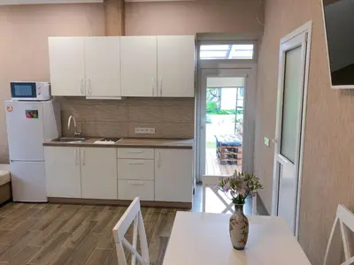 a kitchen with white cabinets and a table with flowers on it at Marsas in Zarasai