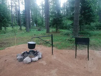a fire pit with a bucket and a grill at NeriPaulis in Ažvinčiai