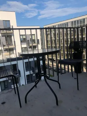 a table and two chairs on a balcony with a building at Ozas Apartment 1 and 2 in Vilnius