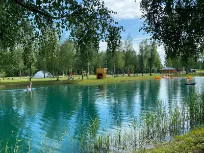 a pond in a park with people swimming in it at Marijampole Camping in Marijampolė