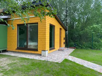 a yellow tiny house in a yard at Marijampole Camping in Marijampolė