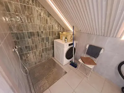 a small bathroom with a washing machine and a chair at Lakefront house in Senoji Varėna in Varėna