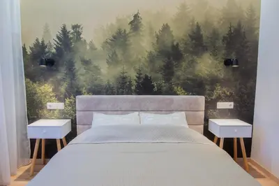 a bedroom with a bed with a forest wall mural at Central and Relaxing apartment in Druskininkai