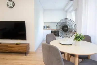 a dining room with a table with chairs and a fan at Central and Relaxing apartment in Druskininkai