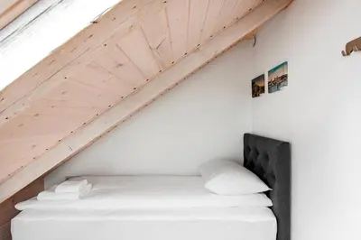 a bed in a room with a wooden ceiling at Small attic rooms in Kaunas old town in Kaunas