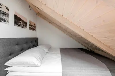 a bed in a room with a wooden ceiling at Small attic rooms in Kaunas old town in Kaunas