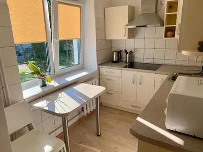 a kitchen with white cabinets and a table and a window at Centro Apartamentai in Zarasai