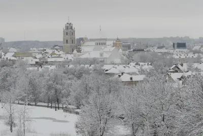 a town covered in snow with a clock tower at Helios Luxury apartment in Vilnius skyscraper in Vilnius