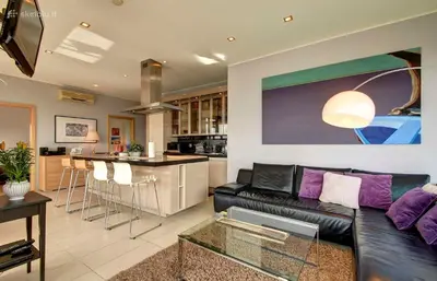 a living room with a black leather couch and a kitchen at Helios Luxury apartment in Vilnius skyscraper in Vilnius