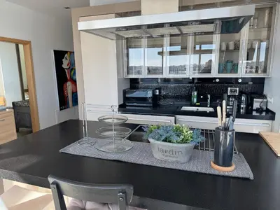 a kitchen with a black counter top with glasses and flowers at Helios Luxury apartment in Vilnius skyscraper in Vilnius