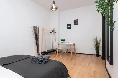 a white room with a bed and a table at The house Vilnius in Vilnius