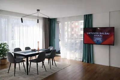 a dining room with a table and chairs and a tv at Centro apartamentai in Birštonas