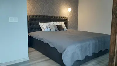 a bedroom with a large bed with a wooden headboard at Jaukūs apartamentai-studija, centre in Šiauliai