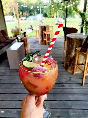 a person holding a drink with a striped straw at Natur Camp Birštonas in Birštonas