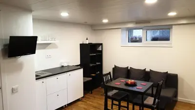 a living room with a small table and a kitchen at Muziejaus 10 studija in Anykščiai