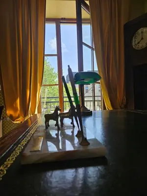 a couple of figurines on a table in front of a window at Barrister's apartments with fireplace in Šiauliai