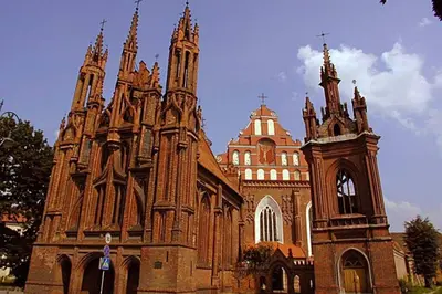 an old church with a clock tower in front of it at PRIVATE FREE SAUNA & 4 bedrooms Old Town Rooftop Apartment in Vilnius