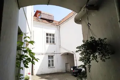 an archway leading to a white building with a courtyard at PRIVATE FREE SAUNA & 4 bedrooms Old Town Rooftop Apartment in Vilnius