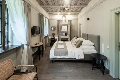 a bedroom with a bed and a desk and a television at Zyplių Dvaro Oficina Viešbutis in Lukšiai