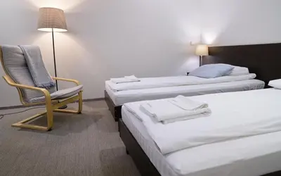 a room with three beds and a chair and a lamp at Jundula in Šakiai