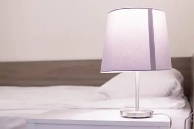 a white lamp on a nightstand next to a bed at Jundula in Šakiai