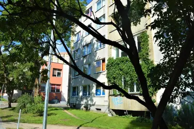 a tall building in a park next to a tree at Slucko Central Studio Apartment near River in Vilnius