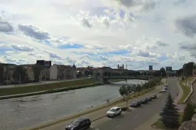 a river with cars parked on the side of a road at Slucko Central Studio Apartment near River in Vilnius